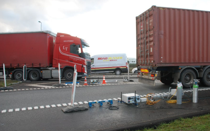 Trailer trucks passing in front of opus remote sensing device in Denmark
